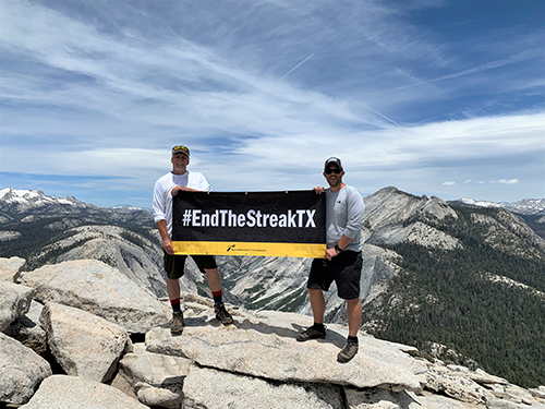 Hikers holding EndTheStreakTX banner at the top of Half Dome